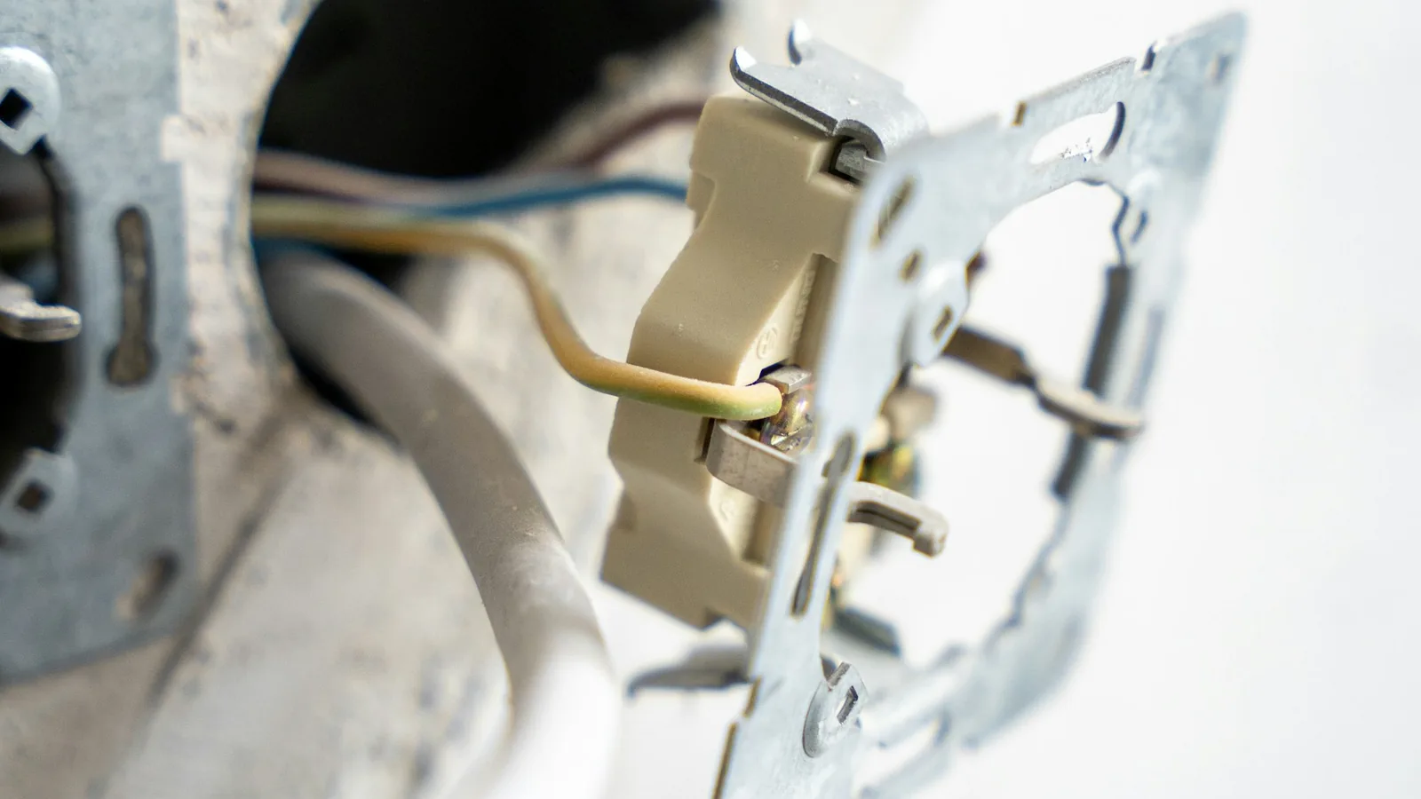 Geöffnete Wandöffnung mit Leitungen und ausgebautem Schalter-Einsatz während einer Elektroinstallation