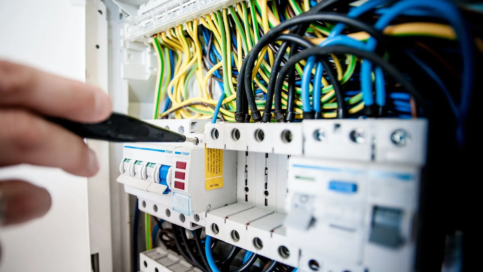 Elektrofachkraft prüft Komponenten und Verdrahtung in einem geöffneten Stromverteiler